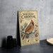 A vintage-style poster titled "Northern Cardinal in Winter" featuring a red cardinal bird perched on a branch with pine needles and berries.