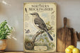 A vintage-style illustration of a Northern Mockingbird is displayed on a shelf, accompanied by a wooden cutting board and a potted plant.
