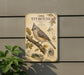 a metal sign with an illustration of a small bird, specifically an oak titmouse, perched on a branch.