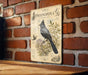 a vintage-style illustration of a bird, specifically a Phainopea, perched on a branch with various botanical illustrations surrounding it.
