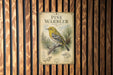 a vintage-style sign with a pine warbler illustration, mounted on a wooden wall.