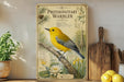 a vintage-style poster of a yellow bird perched on a branch, surrounded by illustrations of plants and flowers, with text providing information about the bird.