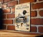A vintage-style metal sign with illustrations of ducks and mergansers, mounted on a brick wall.