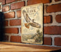 a vintage-style metal sign with a red-tailed hawk illustration, mounted on a brick wall.