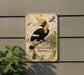 a vintage-style metal sign with a detailed illustration of a hornbill bird, surrounded by various plant illustrations.