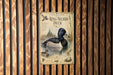 a sign with a duck illustration, mounted on a wooden wall.