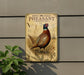 A metal sign featuring a detailed illustration of a ring-necked pheasant rooster, with text describing the bird's features and habitat.