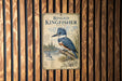 A sign for the "Ringed Kingfisher" is displayed on a wooden wall, featuring a detailed illustration of the bird and its natural habitat.