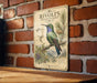 a vintage-style metal sign with an illustration of a hummingbird perched on a branch, surrounded by pine cones and other natural elements.