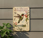 a vintage-style sign depicting a Ruby-throated Hummingbird, with illustrations of the bird, flowers, and a mountain landscape.