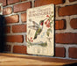 A vintage-style informational sign about the Ruby-Throated Hummingbird is displayed on a brick wall.