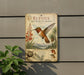a vintage-style informational sign about the Rufous Hummingbird, mounted on a wall next to a plant.