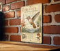a vintage-style metal sign with illustrations and text about the Rufous Hummingbird, which is mounted on a brick wall.