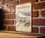 A metal sign with a vintage-style illustration of a sanderling bird, mounted on a brick wall.