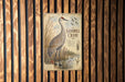 a vintage-style metal sign with an illustration of a sandhill crane standing in a grassy field.