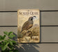 a metal plaque with an illustration of a quail bird, mounted on a wall next to a plant.