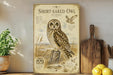 a poster of a short-eared owl, which is a type of owl with distinctive short ears and a unique appearance. The poster is displayed on a wall, surrounded by various kitchen items such as a cutting board, a knife, a bowl, and a potted plant.
