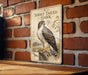 a sign with a picture of a short-tailed hawk, mounted on a brick wall.