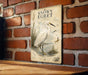 A vintage-style metal plaque with an illustration of a snowy egret standing on a brick wall.