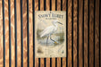 A sign for Snowy Egret Wading, featuring a detailed illustration of a Snowy Egret standing in shallow water with reeds and a bird's egg.