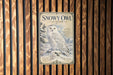 A vintage-style poster of a snowy owl is displayed on a wooden wall.