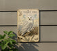 a vintage-style metal sign depicting a snowy owl, with additional illustrations and text providing information about the species.