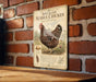 a metal sign with a picture of a speckled chicken, mounted on a brick wall.