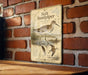 A metal plaque with an illustration of a bird, likely a sandpiper, standing on a brick wall.