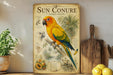 a vintage-style poster of a parrot, specifically a Sun Conure, perched on a branch. The poster includes detailed illustrations and text about the species, such as its physical characteristics, habitat, and behavior. The poster is displayed on a shelf next to a wooden cutting board and a potted plant, creating a homely and decorative atmosphere.