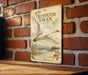 a vintage-style metal sign with a white swan illustration, mounted on a brick wall.