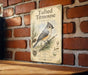 a vintage-style metal sign with illustrations and text, mounted on a brick wall.