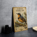 a vintage-style metal sign with a detailed illustration of a bird, placed on a countertop next to some black camera lenses.