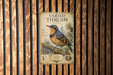 a vintage-style poster of a bird, likely a thrush, mounted on a wooden wall.