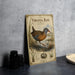 a vintage-style metal sign with a bird illustration, placed on a table next to some black camera lenses.