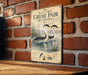 A vintage-style sign for Western Grebes, a type of water bird, is displayed on a brick wall.