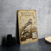 a vintage-style metal sign with illustrations and text, placed on a table next to some black camera lenses.