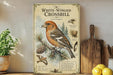 a vintage-style illustration of a White-winged Crossbill bird, with detailed illustrations of the bird, pine cones, and other natural elements. The text on the illustration provides information about the bird, including its habitat, size, and behavior.
