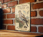 A vintage-style metal sign featuring an illustration of a white-winged dove, mounted on a brick wall.