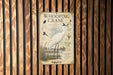 A vintage-style poster of a Whooping Crane is displayed on a wooden wall.