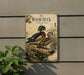 A vintage-style metal sign with illustrations of wood ducks and a log, mounted on a wall.