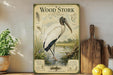 A vintage-style metal poster of a wood stork is displayed on a shelf, accompanied by a wooden cutting board and a potted plant.