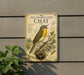 A vintage-style metal sign with a detailed illustration of a yellow-breasted chat bird perched on a branch, surrounded by foliage and a nest.