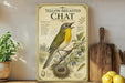 A vintage-style poster of a yellow-breasted chat bird is displayed on a shelf, accompanied by a wooden cutting board and a potted plant.