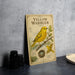 A vintage-style metal sign with illustrations and text about yellow warblers, placed on a countertop next to some camera equipment.