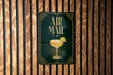 a sign that reads "AIR MAIL" with a picture of a cocktail on it, mounted on a wooden wall.