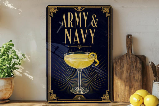 A framed poster with the text "ARMY & NAVY" and an illustration of a cocktail glass with a lemon twist, placed on a wooden shelf next to a cutting board and a potted plant.