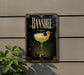 A framed poster of a cocktail with a lemon on top, hanging on a wall next to a plant.
