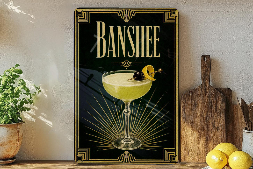 A framed poster of a cocktail with a lemon twist and a cherry on top, placed on a wooden shelf next to a cutting board and a potted plant.