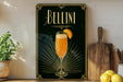 A framed poster of a champagne glass with a slice of orange on a black background, surrounded by decorative elements such as a wooden cutting board and a potted plant.