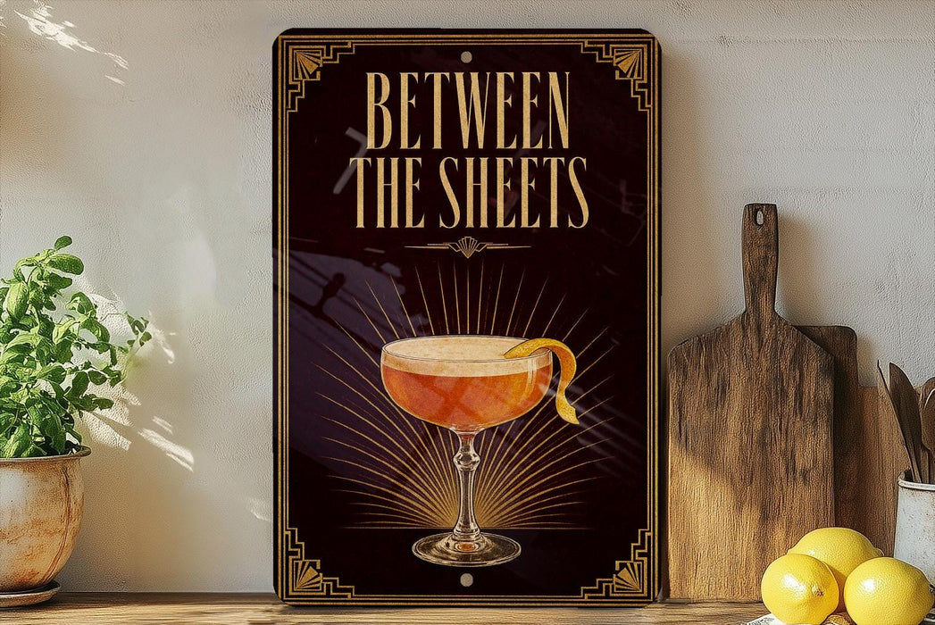 A decorative sign with the text "BETWEEN THE SHEETS" and an illustration of a cocktail glass with a lemon twist.